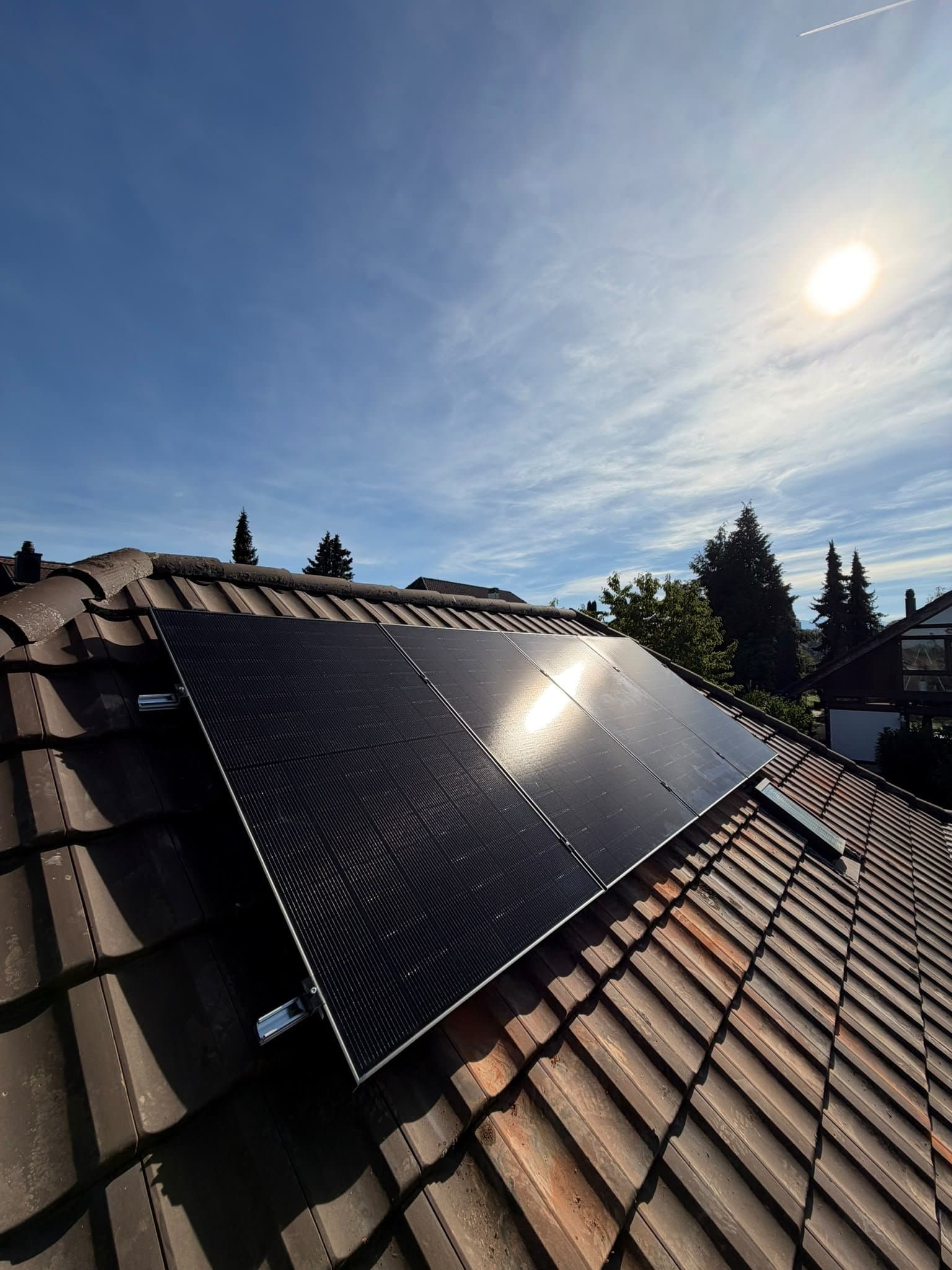 Solarmodule auf dem Ziegeldach im Gegenlicht, seitlich die Dachhaken